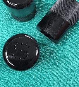 A black bottle and cap on top of a green towel.