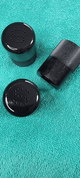 A black bottle and cap on top of a green towel.